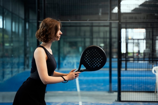 Side view woman playing paddle tennis