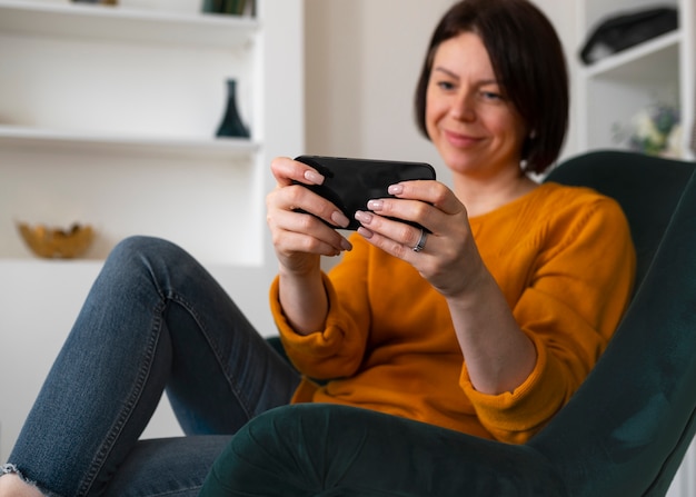 Foto gratuita donna di vista laterale che gioca con il suo telefono