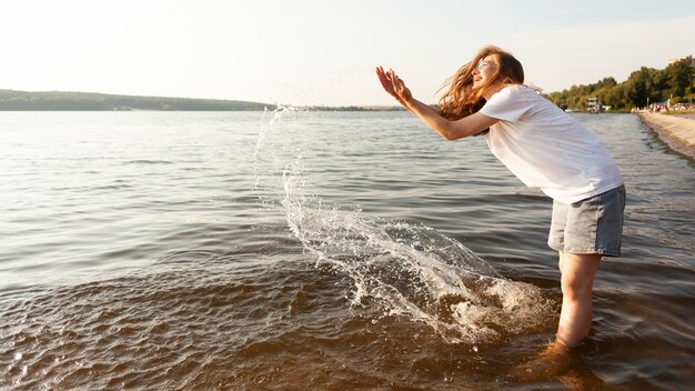 Side view of woman playing with water by the lake