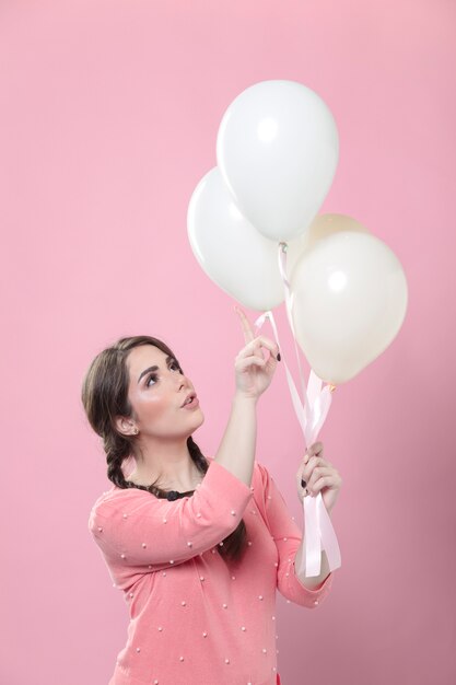 Side view of woman pointing at the balloons she holding