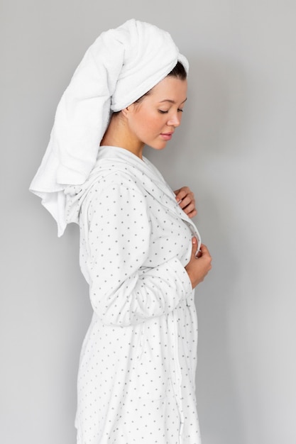 Free photo side view of woman posing in bathrobe and towel