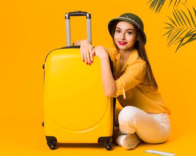 Side view of woman posing next to her luggage