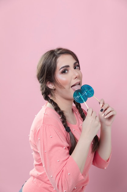 Side view of woman posing silly while licking lollipops