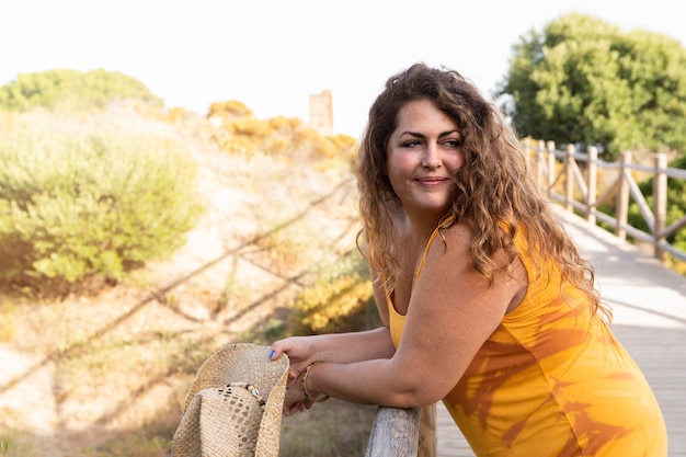 Free photo side view of woman posing while leaning on wooden fence