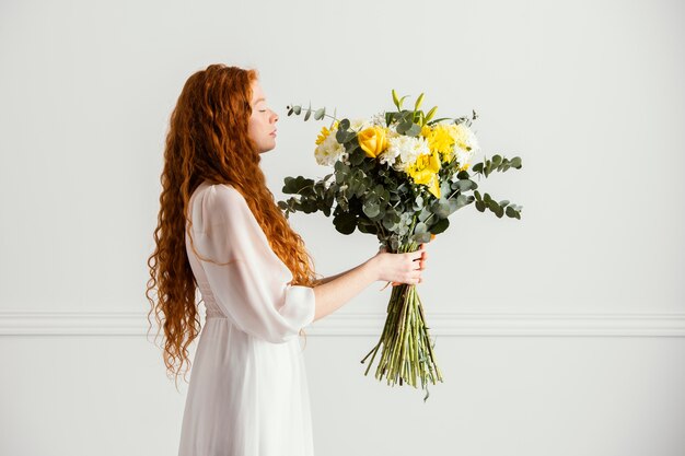Side view of woman posing with beautiful bouquet of spring flowers