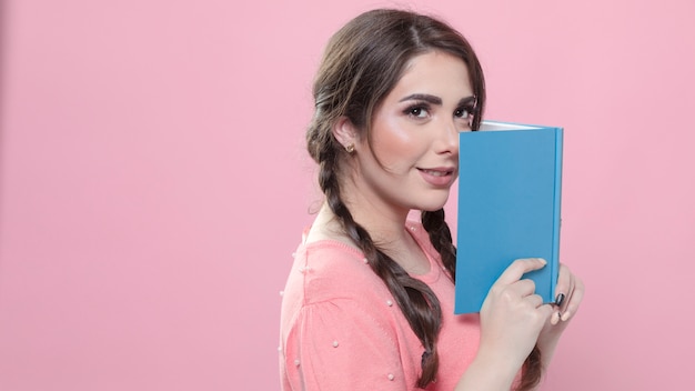 Side view of woman posing with book close to her face