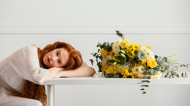 Vista laterale della donna in posa con bouquet di fiori primaverili sul tavolo