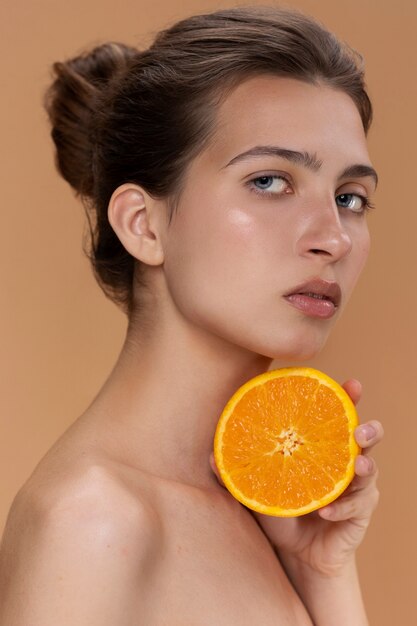 Вид сбоку женщина позирует с оранжевой половинкой