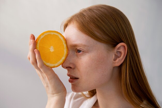 Side view woman posing with orange slice