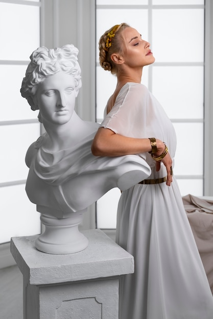 Free photo side view woman posing with statue