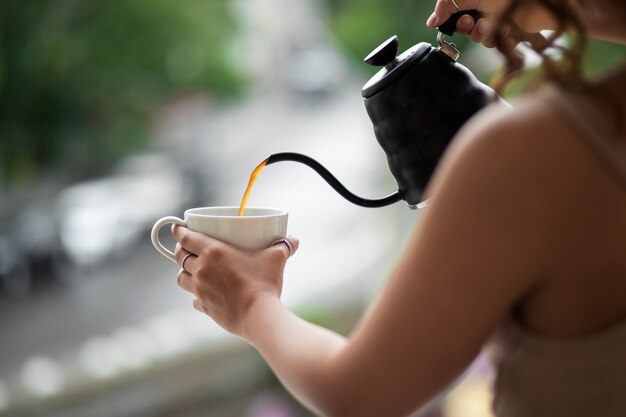 コーヒーを注ぐ側面図の女性
