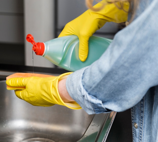 Free photo side view of woman pouring dish soap on sponge