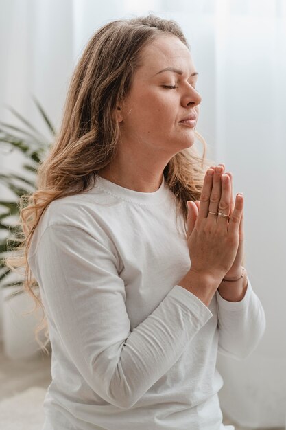 Side view of woman praying at home