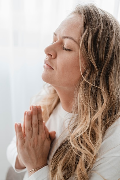 Free photo side view of woman praying with eyes closed