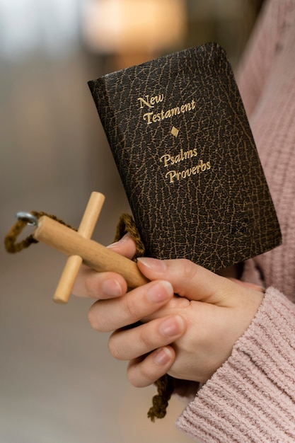 Free photo side view of woman praying with wooden cross and bible