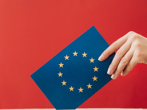 Side view woman putting an european voting card in a box 