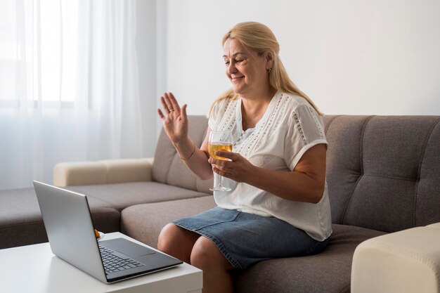 Free photo side view of woman in quarantine having a drink with laptop