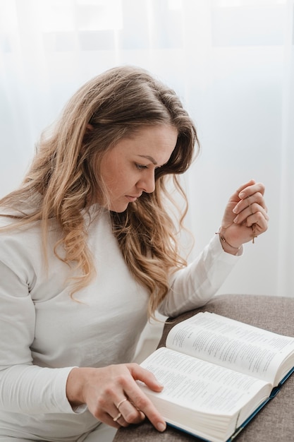 Side view of woman reading from bible at home