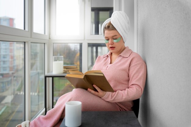 Вид сбоку женщина читает дома
