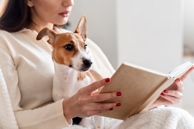 Vista laterale della lettura della donna mentre si tiene il suo cane