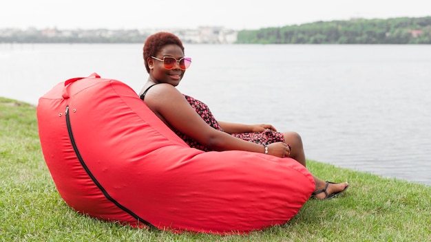 Free photo side view of woman relaxing outdoors on bean bag