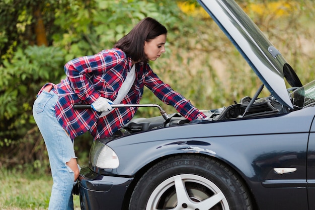 車のエンジンを修理する女性の側面図