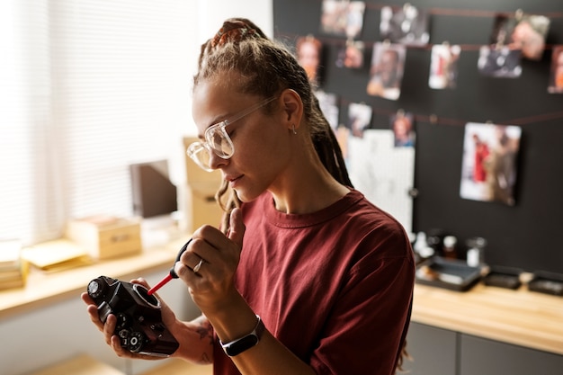 Side view woman repairing photo camera