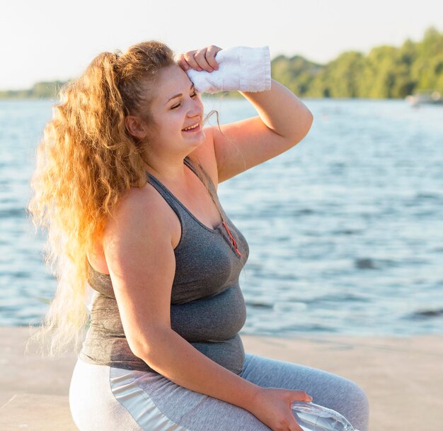 Side view of woman resting after working out by the lake