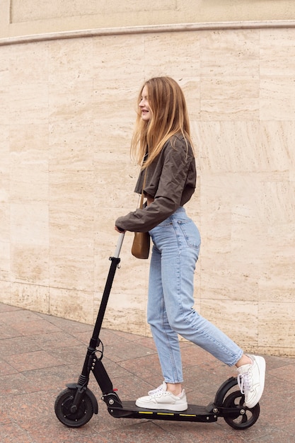 Side view of woman riding electric scooter outdoors