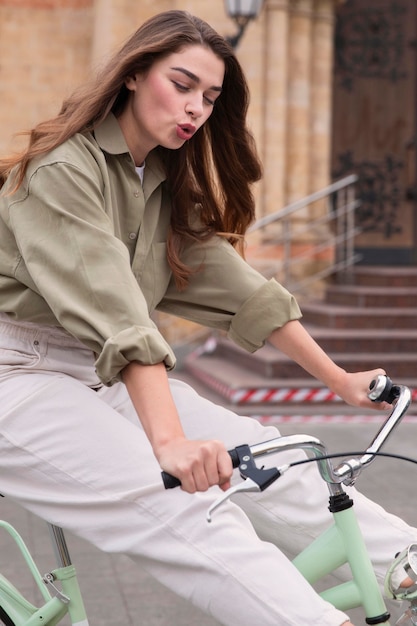 Vista laterale della donna in sella alla sua bicicletta in città all'aperto