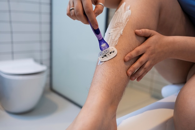 Free photo side view woman shaving at home