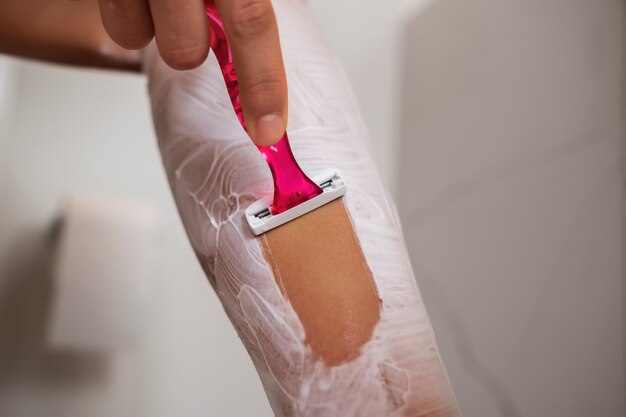 Side view woman shaving leg