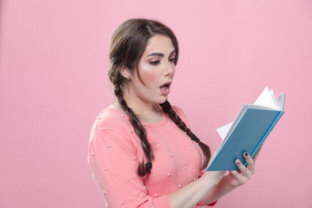 Side view of woman shocked by what she's reading in a book