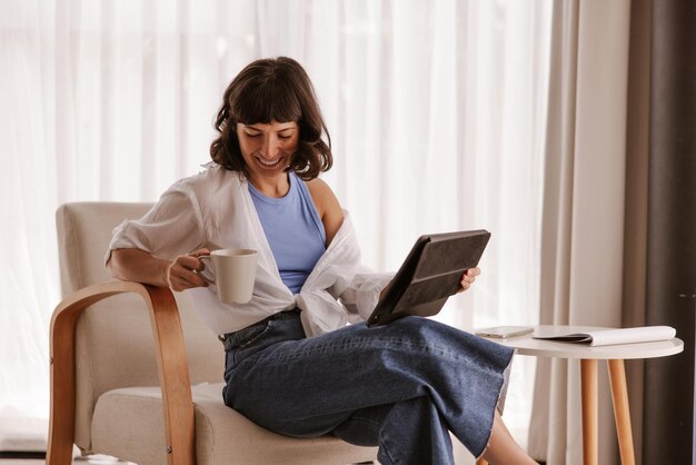 The side view of woman sitting in chair looking at cup of coffee