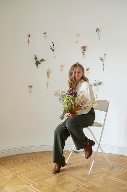 Free photo side view woman sitting on chair with flowers
