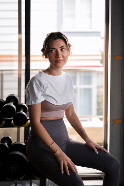 Free photo side view woman sitting at gym