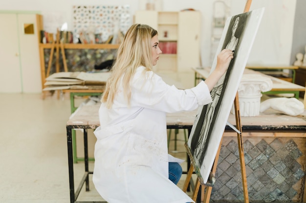 Side view of woman sketching sculpture on canvas