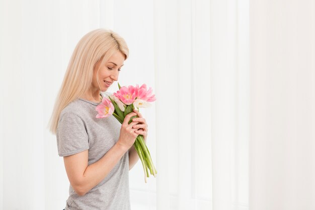 Side view woman smelling flowers bouquet