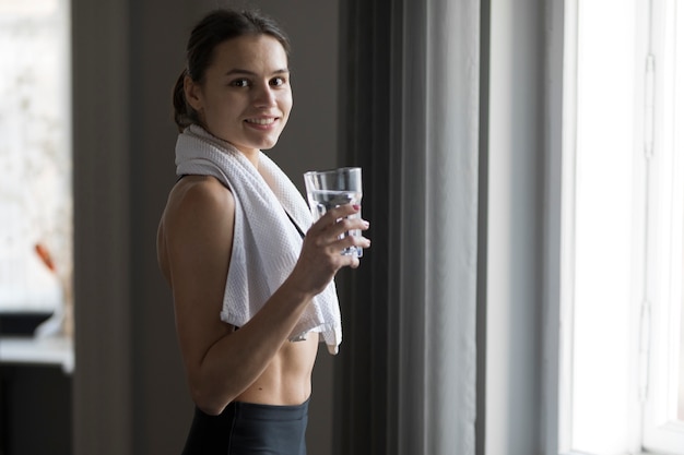 Side view of woman smiling and holding a glass of water
