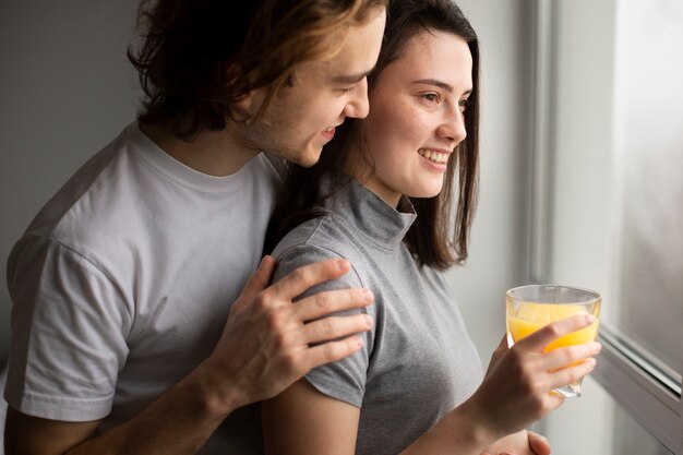 Vista laterale della donna che sorride mentre tenendo il succo d'arancia con il ragazzo