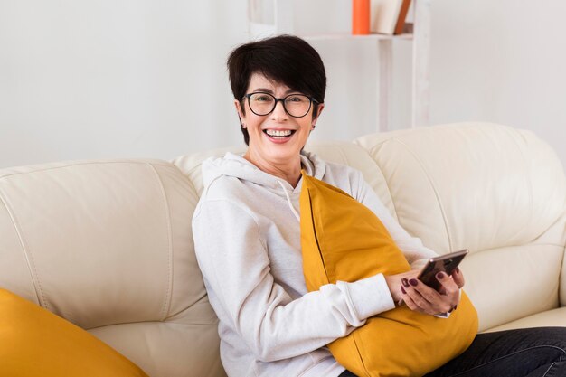 Side view of woman on sofa with smartphone