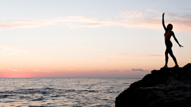 Side view woman in sportswear standing on a coast with copy space