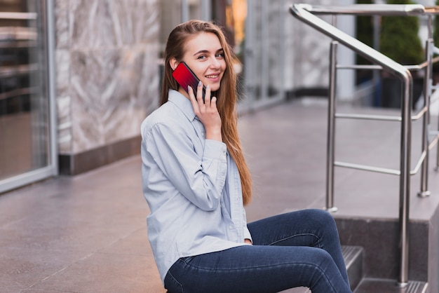 Free photo side view woman on stairs talking over phone