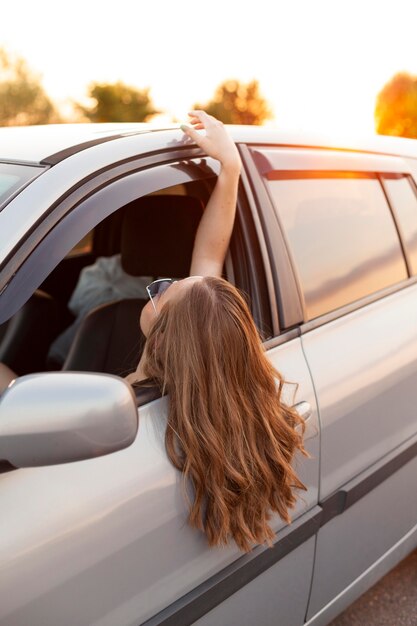 Side view of woman sticking her head of the car outdoors