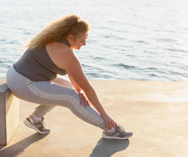 Side view of woman stretching by the lake with copy space