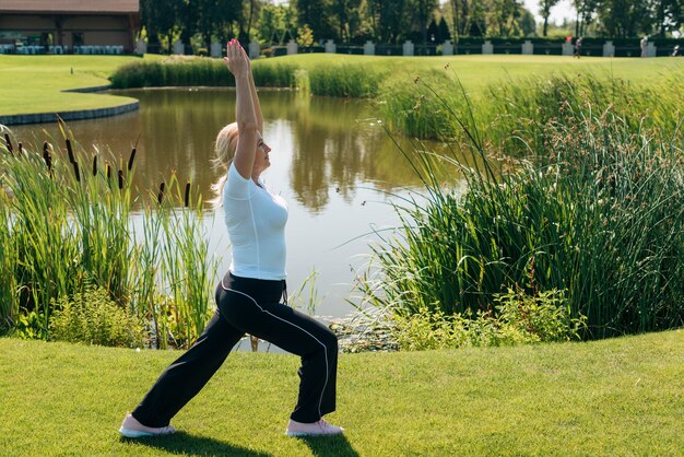 Side view woman stretching near the lake