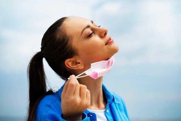 Side view woman taking off face mask