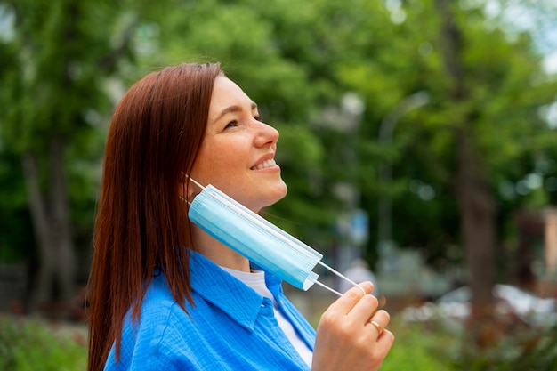 Side view woman taking off mask