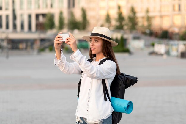 旅行中にスマートフォンで写真を撮る女性の側面図