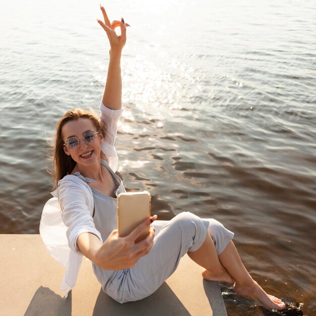 Side view of woman taking a selfie by the lake